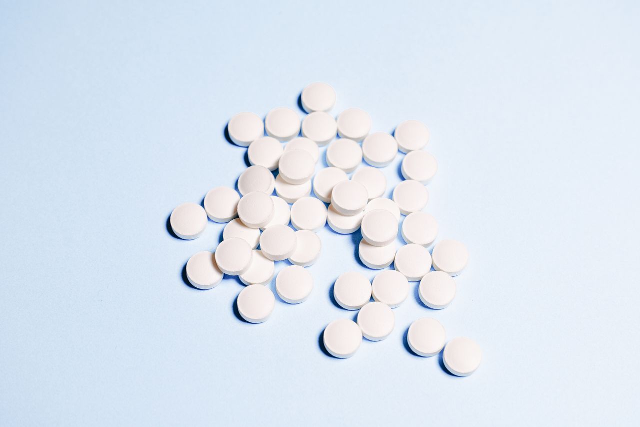 A collection of white tablets scattered on a light blue surface, perfect for health-related content.